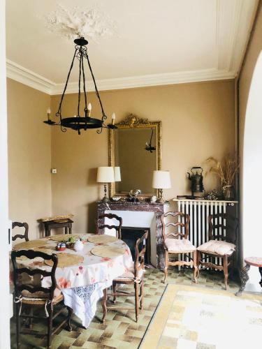 une salle à manger avec une table, des chaises et un miroir dans l'établissement Le Vieux Manoir, à Carolles