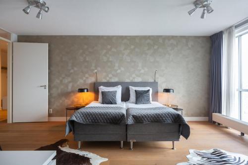 - une chambre avec un grand lit et deux lampes dans l'établissement BizStay Harbour I Scheveningen Apartments, à Scheveningen