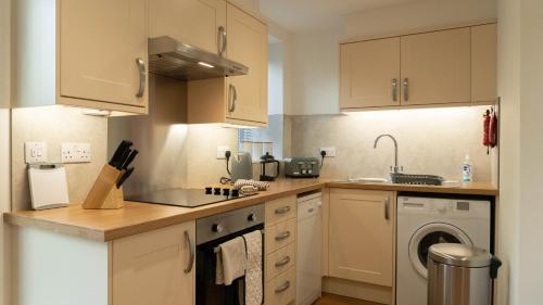 a kitchen with white cabinets and a washer and dryer at Hill Of Oaks in Windermere