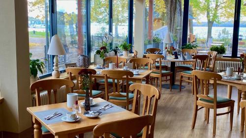 a restaurant with wooden tables and chairs and windows at Badehaus Hotel & Restaurant in Neubrandenburg