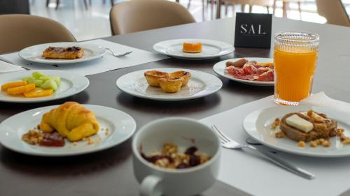 a table with plates of breakfast foods and a glass of orange juice at QH Praia de Quiaios in Praia de Quiaios