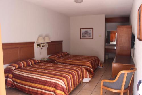a hotel room with two beds and a chair at Hotel La Villa in Torreón