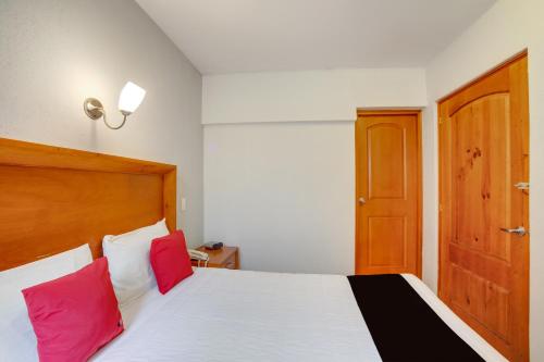 a bedroom with a white bed with two red pillows at Hotel Patzcuaro in Pátzcuaro