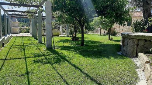 une cour verdoyante avec une clôture et des arbres dans l'établissement O Forno Casa Ferrador Ribeira Sacra, à Sober