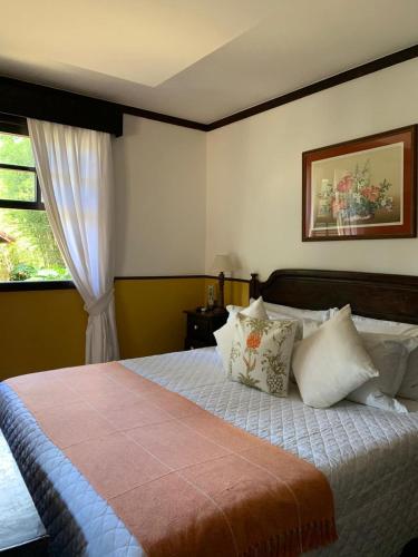 a bedroom with a bed with pillows and a window at Hotel Capim Limão Itaipava in Itaipava
