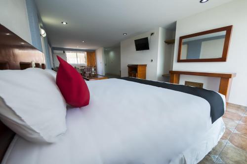 a bedroom with a large white bed with red pillows at Suites de Reyes in Irapuato