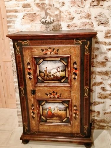 a wooden cabinet with three drawers with paintings on it at Maison en Pierre in Fiastra