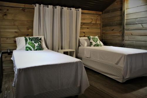 two beds in a room with wooden walls at Garten Chalés in Pomerode