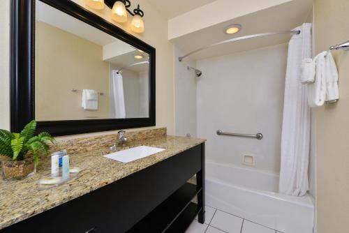 a bathroom with a sink and a tub and a mirror at Blu Pacific Hotel in Monterey