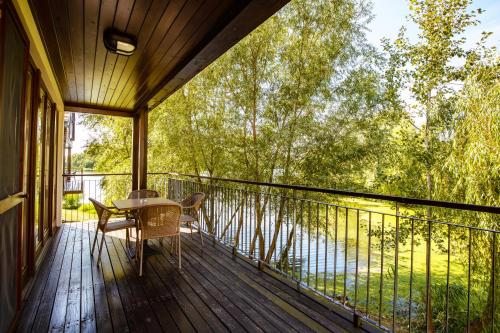 a porch with a table and chairs on a balcony at Tisza Balneum Hotel in Tiszafüred