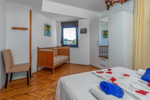 a bedroom with a bed and a chair and a crib at Maestral Apartments in Malinska