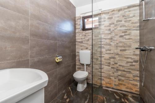 a bathroom with a toilet and a glass shower at Maestral Apartments in Malinska