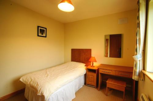 1 dormitorio con cama, escritorio y lámpara en Doonbeg Holiday Homes, en Doonbeg