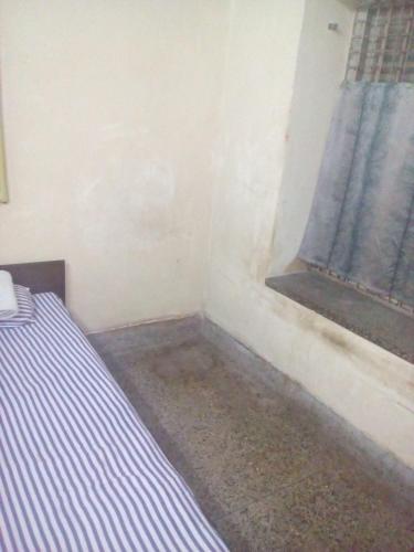 Cette petite chambre comprend un lit et une fenêtre. dans l'établissement APRO, à Kolkata