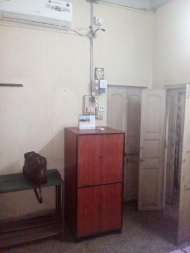 Cette chambre comprend une commode en bois et une table. dans l'établissement APRO, à Kolkata