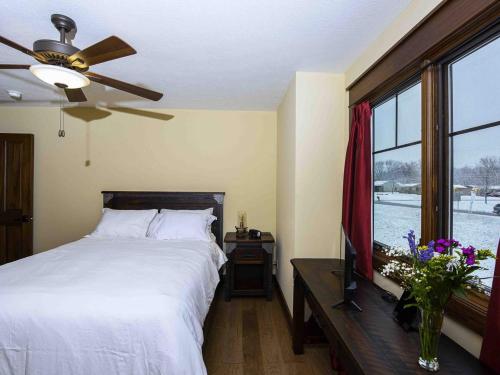 Schlafzimmer mit einem Bett, einem Deckenventilator und einem Fenster in der Unterkunft Purple Skies Homestead in North Royalton