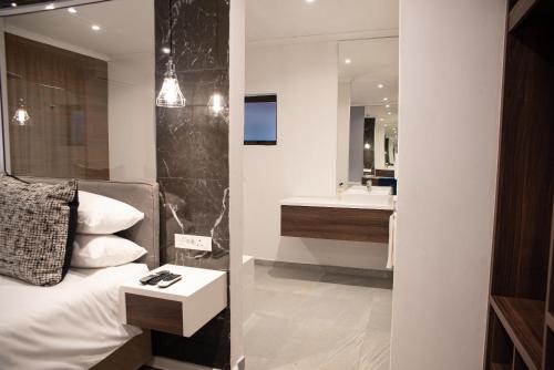 a bedroom with a bed and a sink and a mirror at The Royal Bryanston in Johannesburg