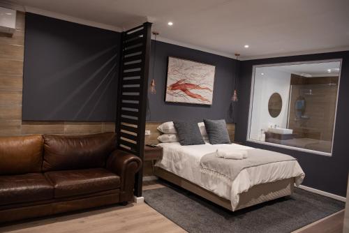 - une chambre avec un lit, un canapé et un miroir dans l'établissement The Royal Bryanston, à Johannesbourg