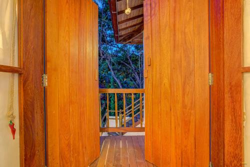 a wooden door leading to a porch with a balcony at A Casa de Gabriella in Itacaré