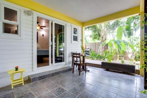 a porch with a table and chairs and a window at Driftwood Gardens Guesthouse in Placencia Village