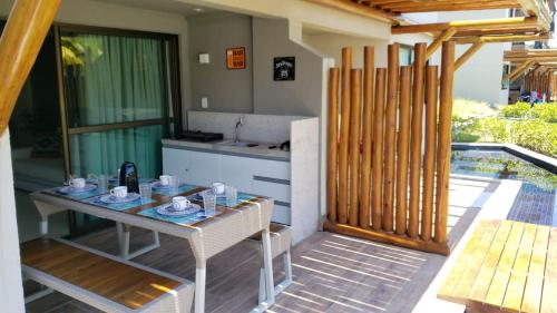 a table and chairs on a patio with a kitchen at La Fleur Polinésia in Porto De Galinhas