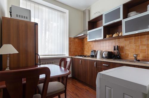 基辅Kyiv High Standard Apartment的配有木制橱柜、桌子和椅子的厨房