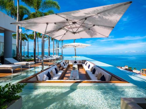 a resort infinity pool with chairs and an ocean view at PIER 57- 309 Beautiful 2 BR Condo in Romantic Zone in Puerto Vallarta