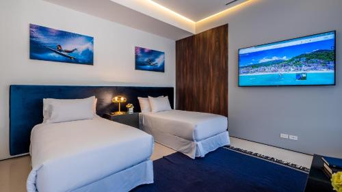 a hotel room with two beds and a flat screen tv at PIER 57- 309 Beautiful 2 BR Condo in Romantic Zone in Puerto Vallarta