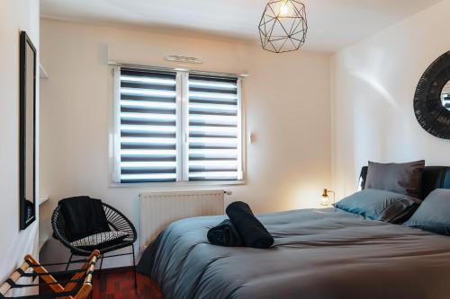 a bedroom with a bed and a chair and a window at La Villetta S Blotzheim - Appartement de Standing in Blotzheim
