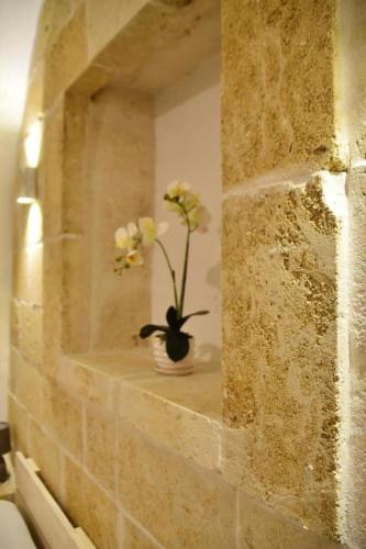 a stone wall with a vase with flowers in it at Casetta dello Scrittore in Ostuni