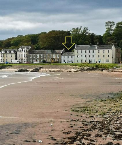 a building with a yellow arrow on it next to a beach at Beside the Bay in Millport
