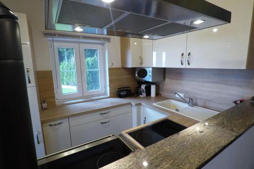 a kitchen with white cabinets and a sink and a window at Panoramablick in Langegg an der Schilcherstraße