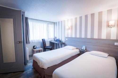 ヴァランシエンヌにあるKyriad Valenciennes Sud - Rouvigniesのベッド2台とデスクが備わるホテルルームです。
