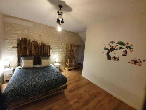 - une chambre avec un lit et un arbre sur le mur dans l'établissement A proximité du zoo de beauval, chambre de charme 