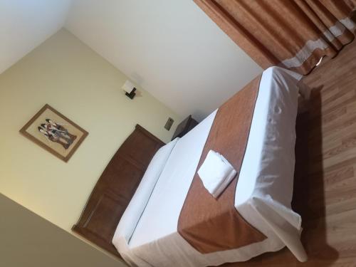 a bedroom with a white bed with a wooden headboard at Hotel Pattaya in Mocejón
