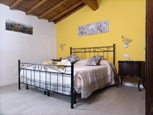 1 dormitorio con cama y pared amarilla en B&B Il Grifo en Bomarzo