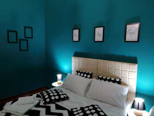 Dormitorio azul con cama con almohadas blancas y negras en CasaCasetta Suite Appartamento Indipendente en Taranto