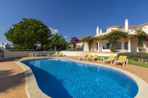 a swimming pool with chairs and a house at Villa with beautiful see views & spacious garden in Ferragudo