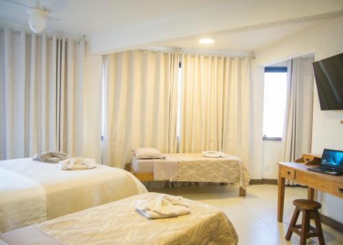 Cette chambre comprend deux lits et un bureau. dans l'établissement Pousada Vieira, à Arraial do Cabo