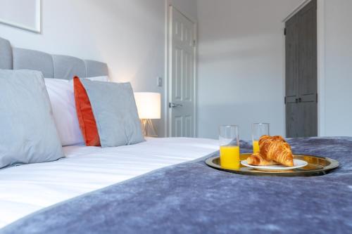 a plate of food and a glass of orange juice on a bed at The Eldern - Spacious, Netflix, free Parking, close to A1 in Peterborough