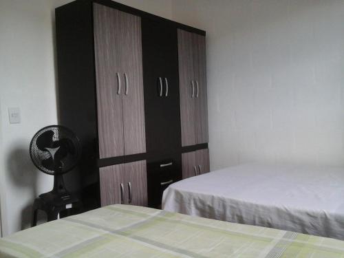 a bedroom with two beds and a large wooden cabinet at Villa Maria DA Luz ROCHA Olimpia in Olímpia
