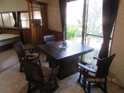 Zimmer mit einem Tisch, Stühlen und einem Fenster in der Unterkunft Guest House Miyazu Kaien - Vacation STAY 99191 in Miyazu