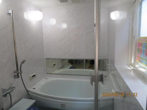 ein Bad mit einer Badewanne und einer Dusche mit einem Spiegel in der Unterkunft Guest House Miyazu Kaien - Vacation STAY 99191 in Miyazu