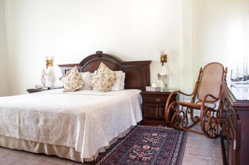 a bedroom with a bed and a chair at Hotel Hacienda Los Laureles in Oaxaca City