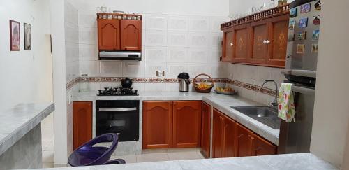 uma cozinha com armários de madeira, um fogão e um lavatório em Habitación Ciudad Cariño em El Cerrito
