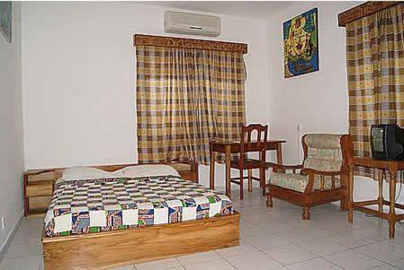 a bedroom with a bed and a table and chairs at Hotel Aurore Lomé in Lomé
