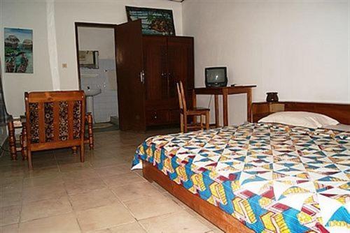 a bedroom with a bed and a table and chairs at Hotel Aurore Lomé in Lomé
