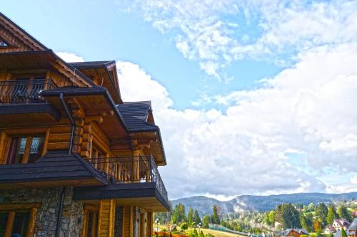 a wooden house with a balcony and mountains in the background at Apartamenty Złoty Groń in Istebna