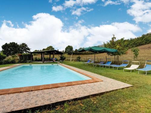 una piscina in un cortile con sedie e ombrelloni di Belvilla by OYO Sorgente a Radicofani