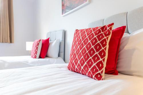 a bed with red and white pillows on it at The Eldern - Spacious, Netflix, free Parking, close to A1 in Peterborough